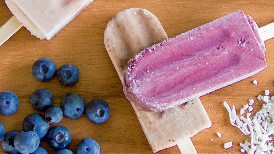 A group of colorful popsicles is displayed, featuring strawberries and coconut shavings on their surfaces. The scene includes fresh strawberries, emphasizing a fruity and refreshing theme. It captures a delightful food moment, ideal for warm days or special occasions.